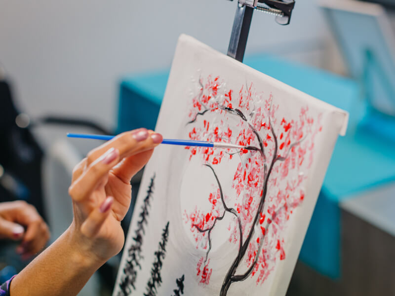 A closeup of a colourful tree being painted on a canvas.